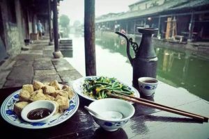 Mangiare cibo cinese e bere vino giallo sul fiume.